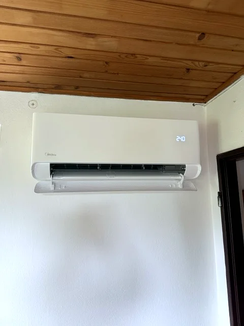 Nástěnná jednotka pod dřevěným stropem chaty