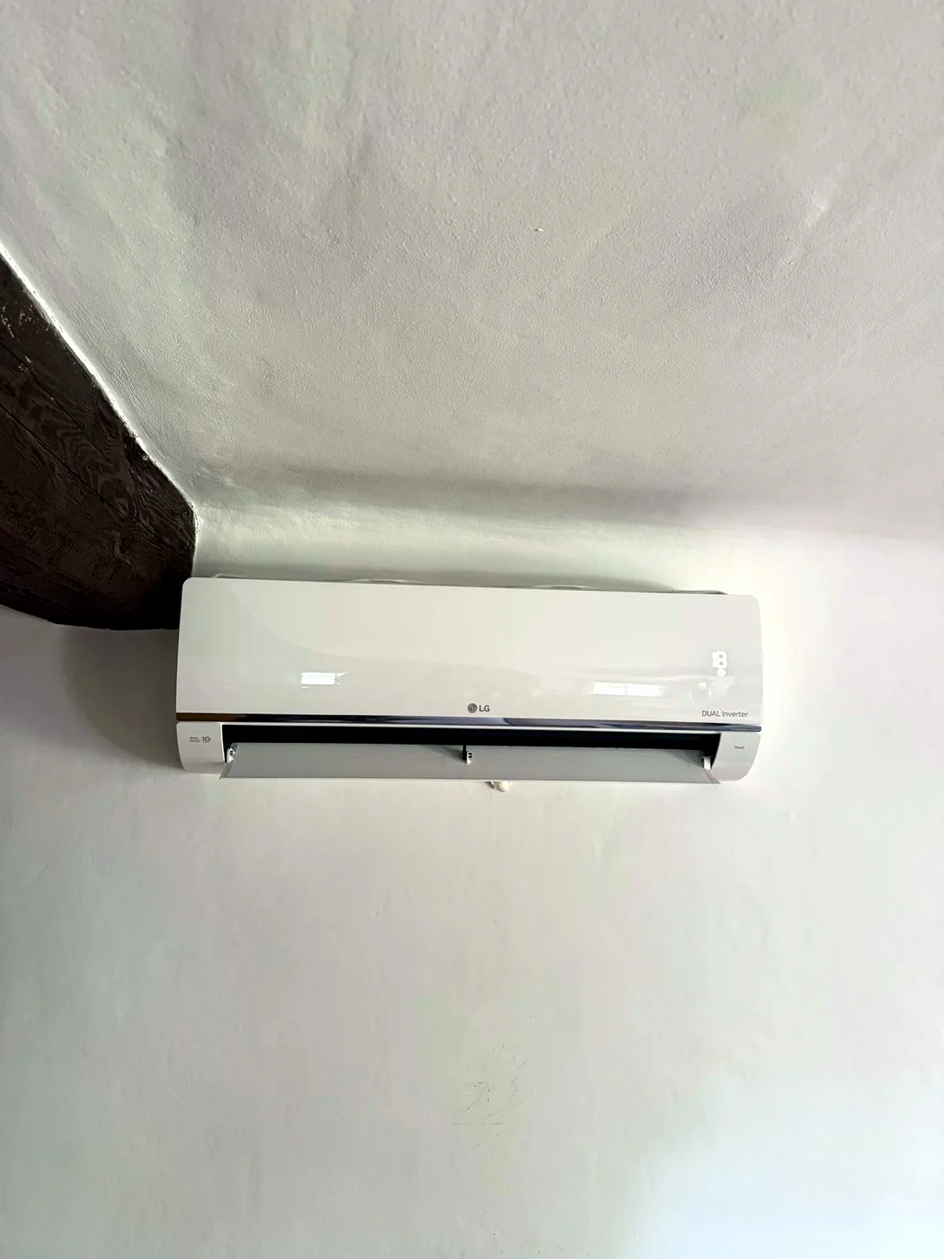 Nástěnná klimatizace LG DUAL Inverter pod dřevěným trámem roubenky