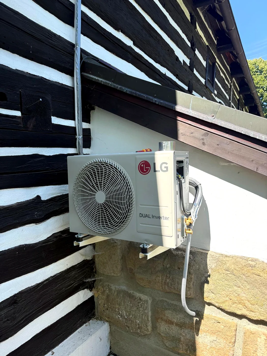 Venkovní jednotka klimatizace LG DUAL Inverter na kamenné podezdívce roubenky
